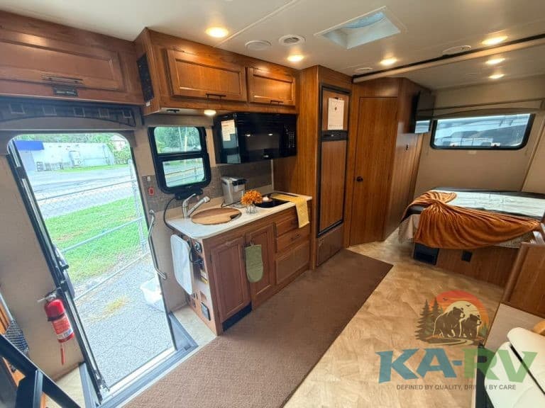 Cozy RV interior with kitchen, sleeping area, and large windows for natural light.