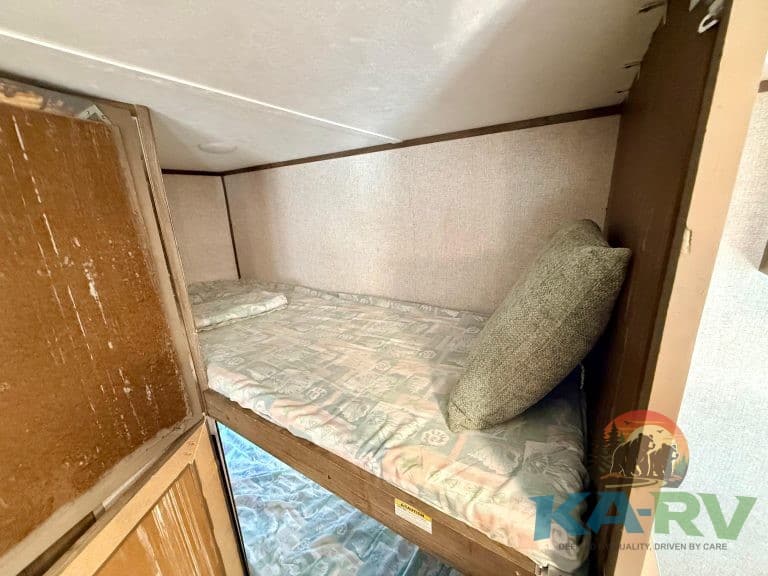 Compact RV bunk bed with mattress and pillow, ideal for space-saving travel accommodations.