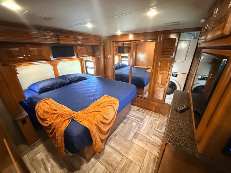 Interior view of a 2018 Fleetwood Discovery RV bedroom with wooden cabinets and a large bed.
