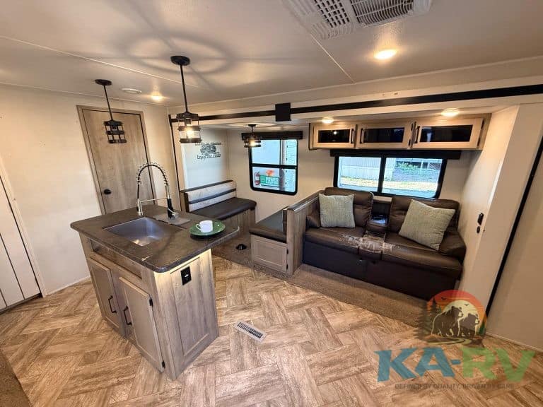 Interior of a modern RV with kitchen, sofa, and large windows for scenic views.