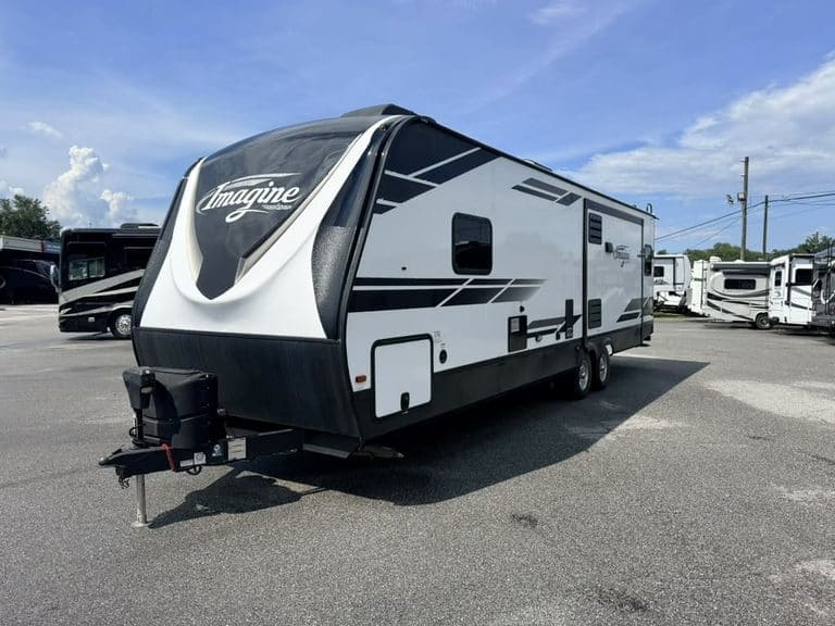 Modern black and white RV travel trailer parked at dealership lot.
