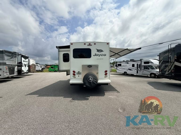 Jayco RV parked in a lot with other RVs under cloudy sky.
