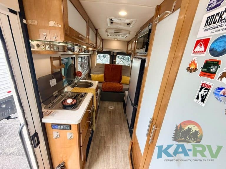 Cozy RV interior with kitchen, seating, and storage for travel comfort.
