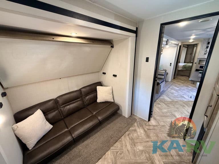 RV interior with a brown leather sofa and cozy pillows, modern living space.