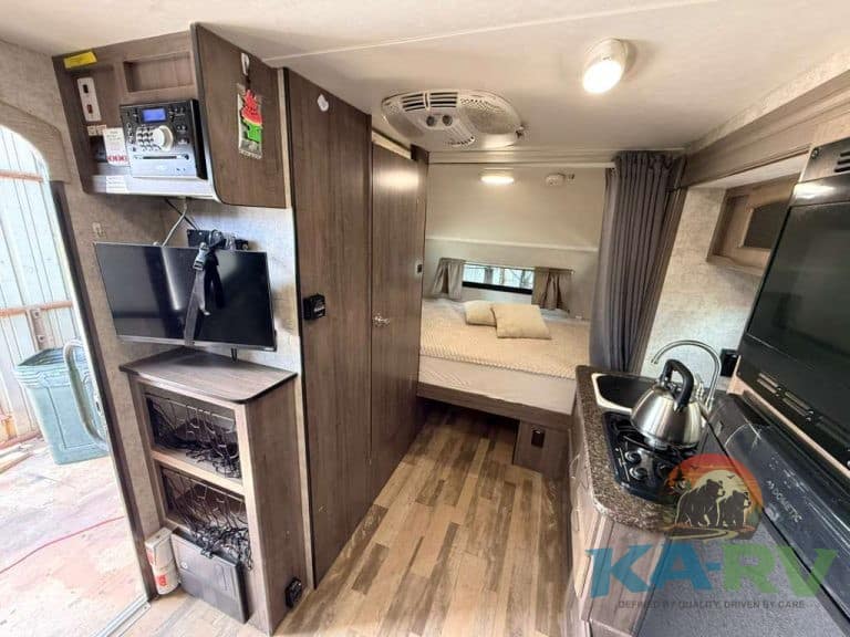 Compact RV interior with kitchen and sleeping area in Winnebago Winnie Drop 1780.