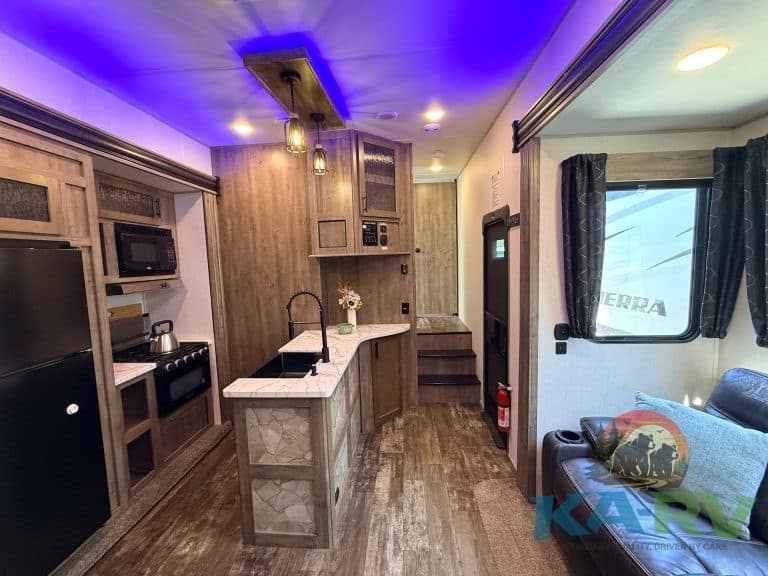 Interior view of a 2021 Forest River Cherokee Wolf Pack 325PACK13 RV, showcasing the kitchen and coz.