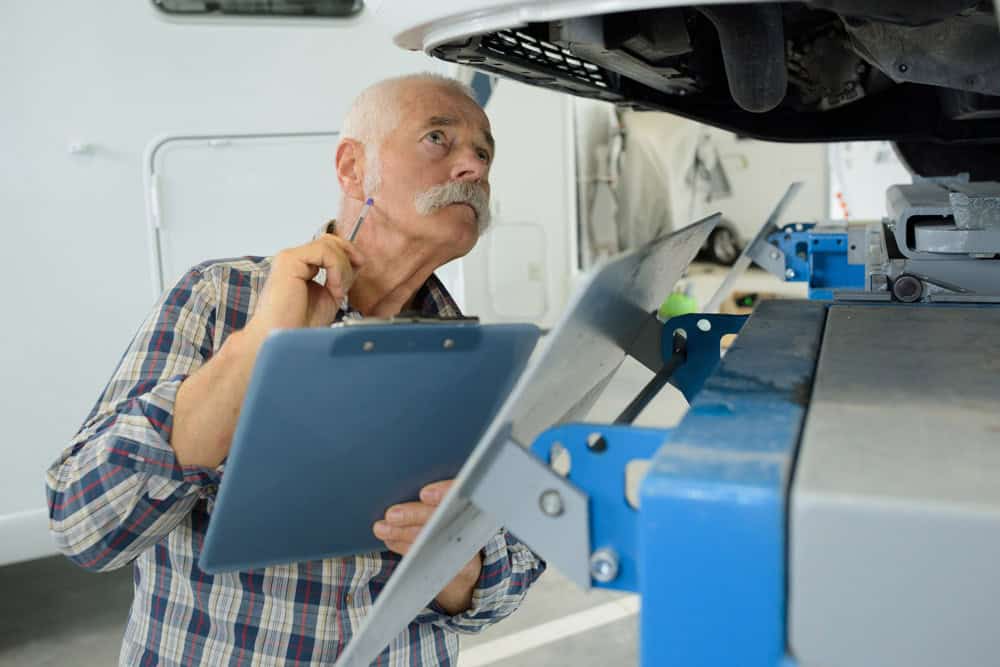 RV maintenance technician checking under an RV for potential problems.