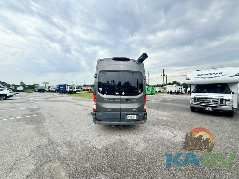 Commercial van parked in RV repair lot with other RVs and trucks nearby.