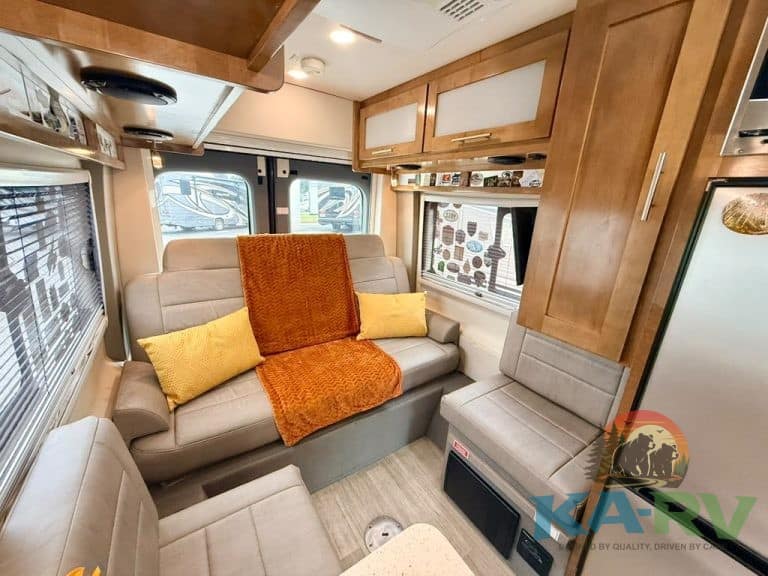 Cozy RV interior with sofa, cushions, and wooden cabinets.