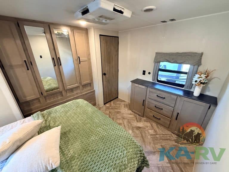 RV bedroom with wardrobe, window, and cozy bedding for optimal comfort.