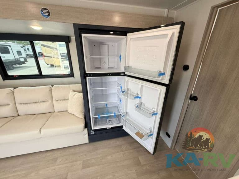 RV refrigerator open showing interior storage and shelves.