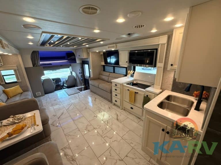 Luxury RV interior with sofa, TV, and kitchen area in Tiffin Allegro Bay 38AB.