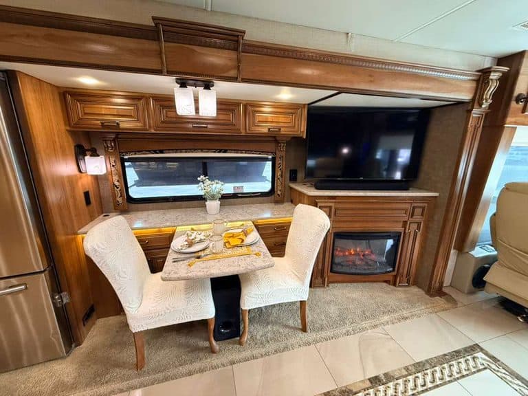 Interior of 2016 Entegra Cornerstone 45B RV with dining area and fireplace.