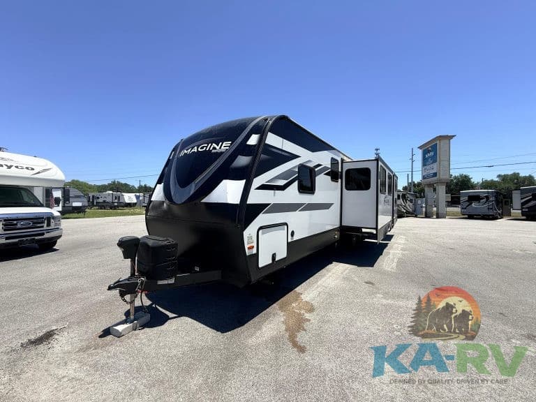 Modern white and black travel trailer with slide-out at KA RV Repair dealership.