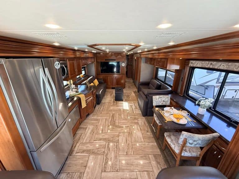 Spacious RV interior with leather sofas, kitchen, and entertainment system.