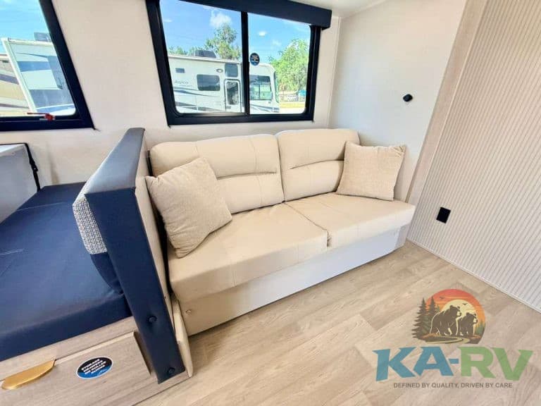 Interior of 2026 Acclaim 2700BH RV with sofa and windows.