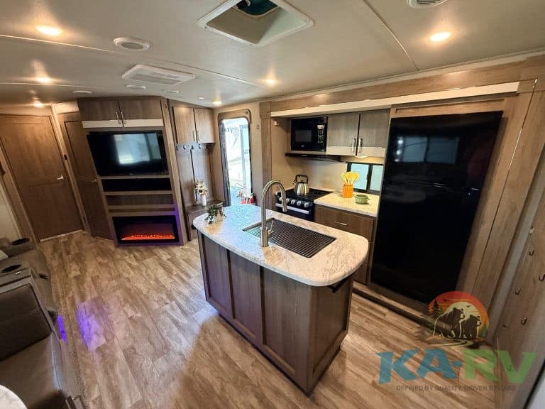 RV kitchen interior with modern appliances and wooden cabinetry.
