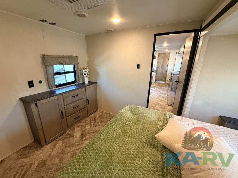 RV bedroom interior with cozy bed, wooden furniture, and natural light.