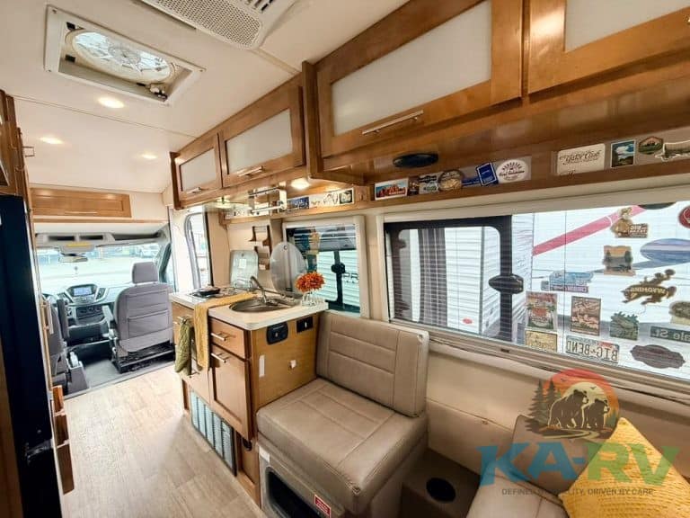 Comfortable RV interior with seating, kitchen, and driving area.
