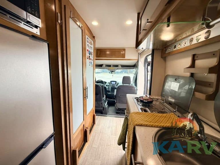 RV kitchen and living space with appliances and seating.