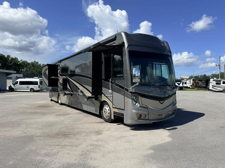 Luxury Class A RV parked outdoors with blue sky and clouds.