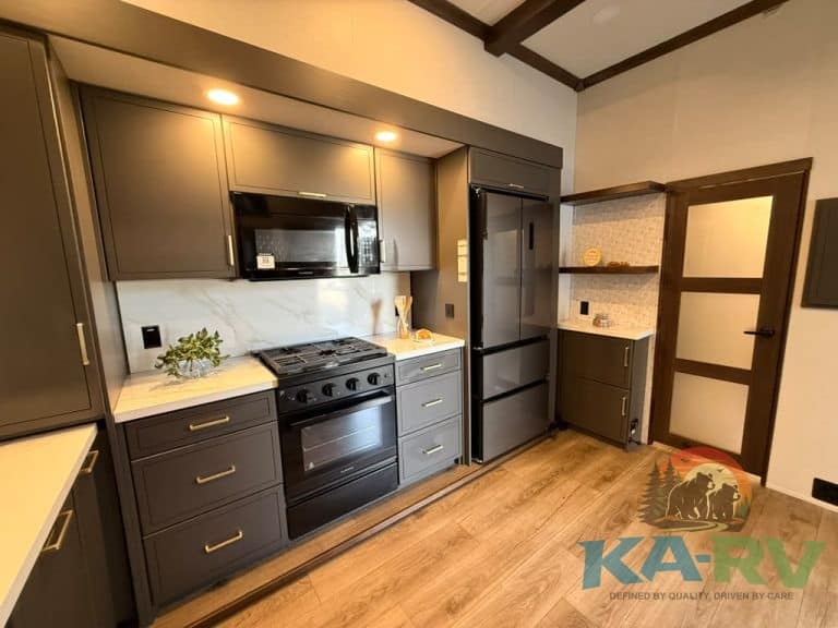 Contemporary kitchen with dark cabinetry, stainless steel appliances, and wooden flooring.