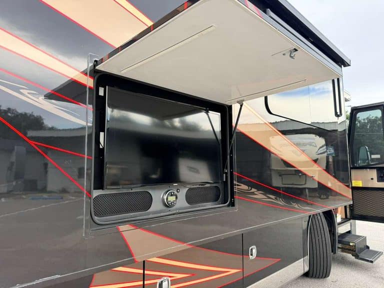 RV kitchen with open slide-out and entertainment center for luxury travel.