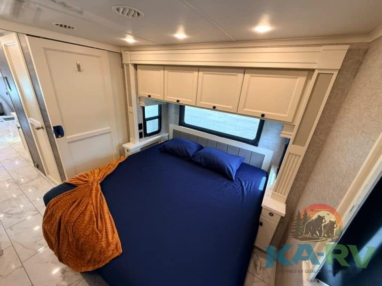 Comfortable bedroom in 2025 Tiffin Allegro Bay RV with large window and storage cabinets.