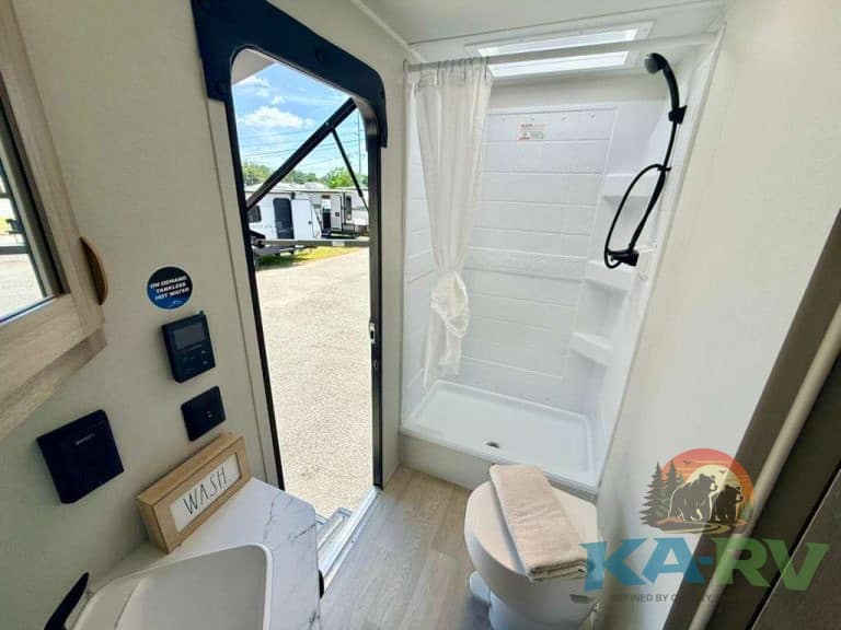 Interior of RV bathroom with shower, toilet, and window view.