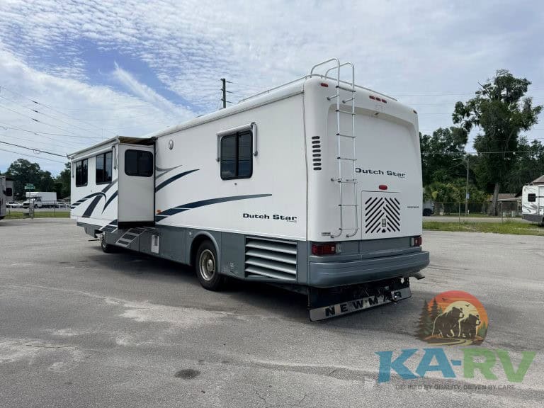 White Dutch Star RV with slide-out and ladder parked outdoors.