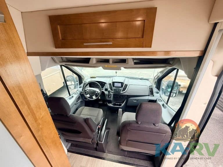 Interior view of RV dashboard with driver and passenger seats.