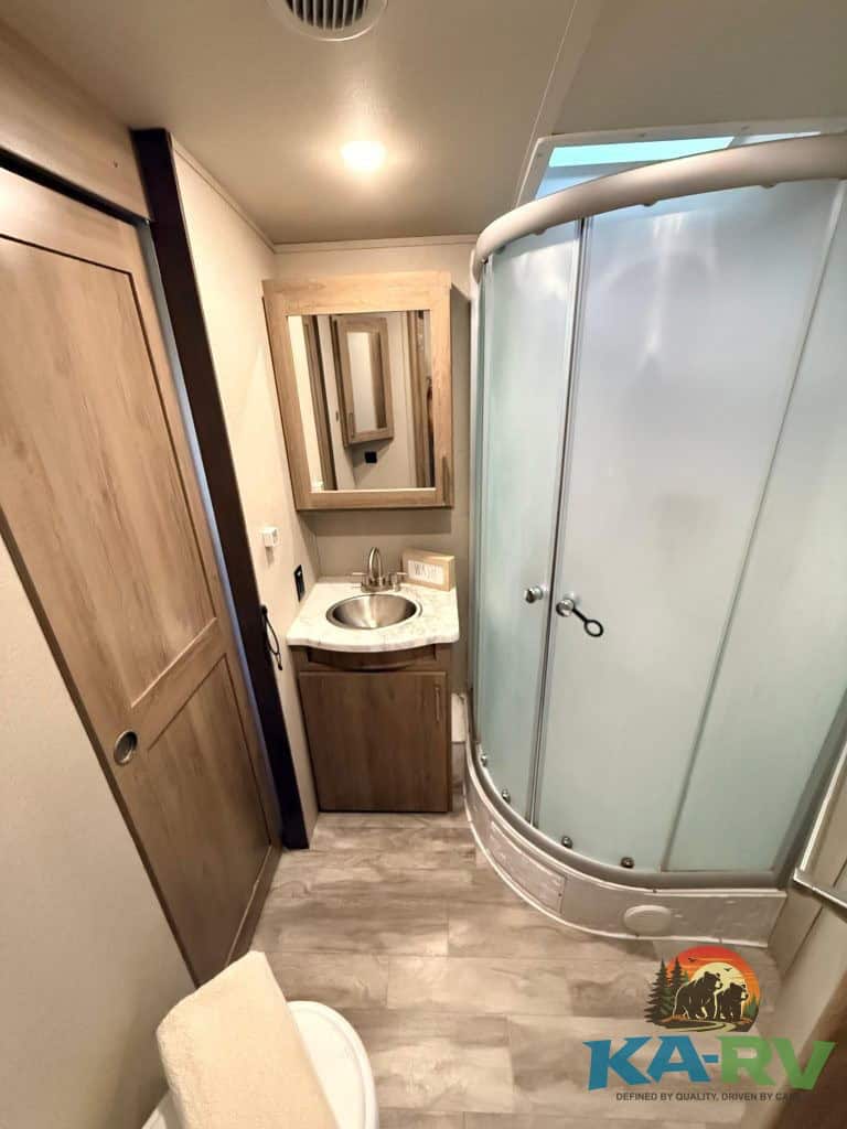 RV bathroom with shower, sink, and wooden accents for optimal comfort and functionality.