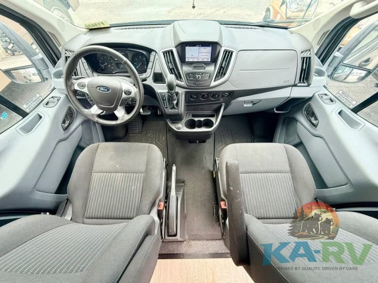 Interior view of a modern RV driver's cabin with dashboard and seats.