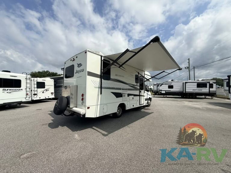 Jayco RV with extended awning in an RV lot under cloudy sky.