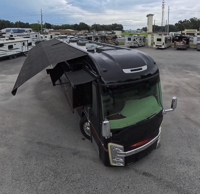 Black RV with extended awning in RV lot, Karv Repair service.