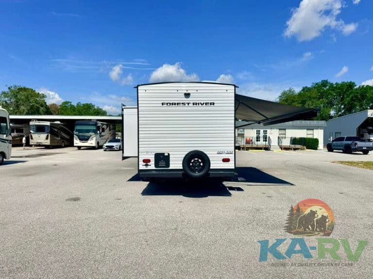Forest River RV trailer with extended awning in lot.