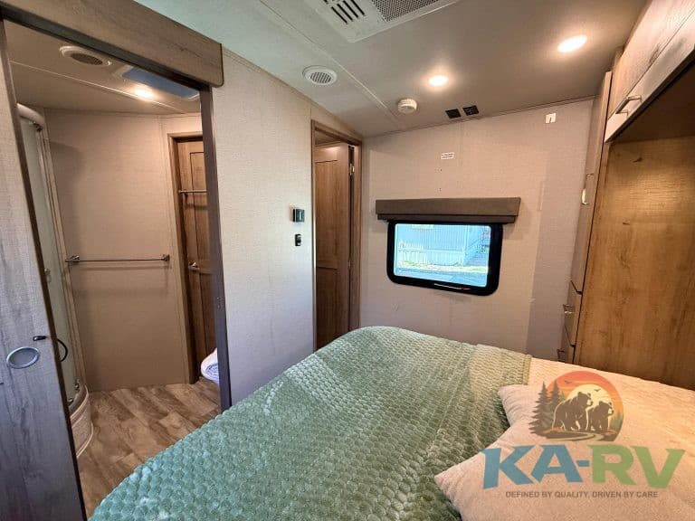 RV bedroom interior with cozy bed and wooden accents, ideal for travel comfort.