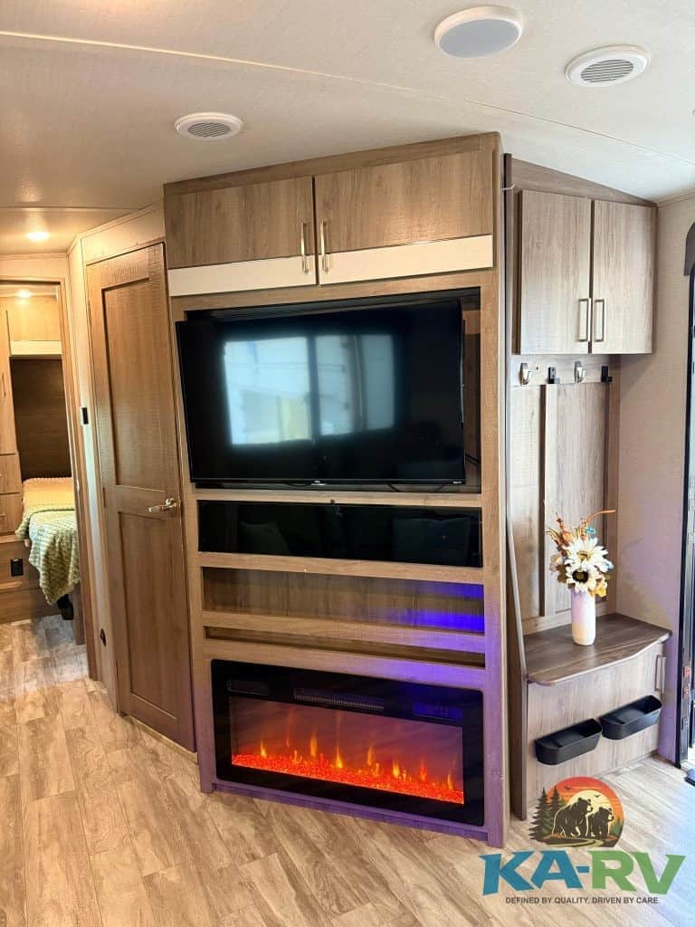 RV entertainment center with fireplace and storage, ideal for Optima RVs, showcasing modern interior.