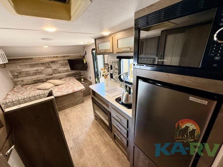 Interior of a compact RV with kitchen, microwave, and sleeping area.