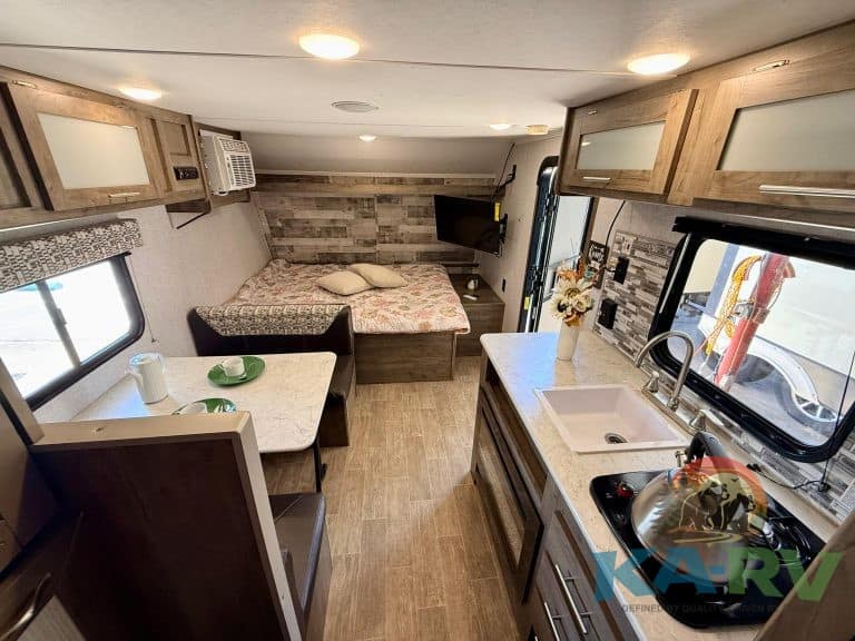RV interior kitchen and sleeping area with compact design, modern appliances, and cozy sleeping spac.