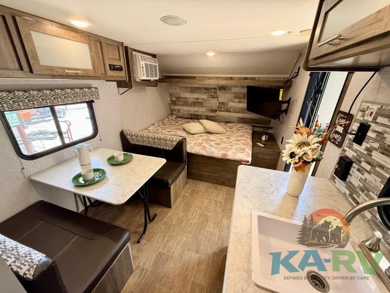 Interior of RV with sleeping area, kitchenette, and seating at KA RV Repair.