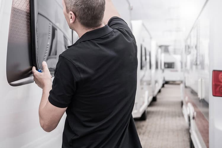 RV service technician performing maintenance on an RV in a professional repair shop.