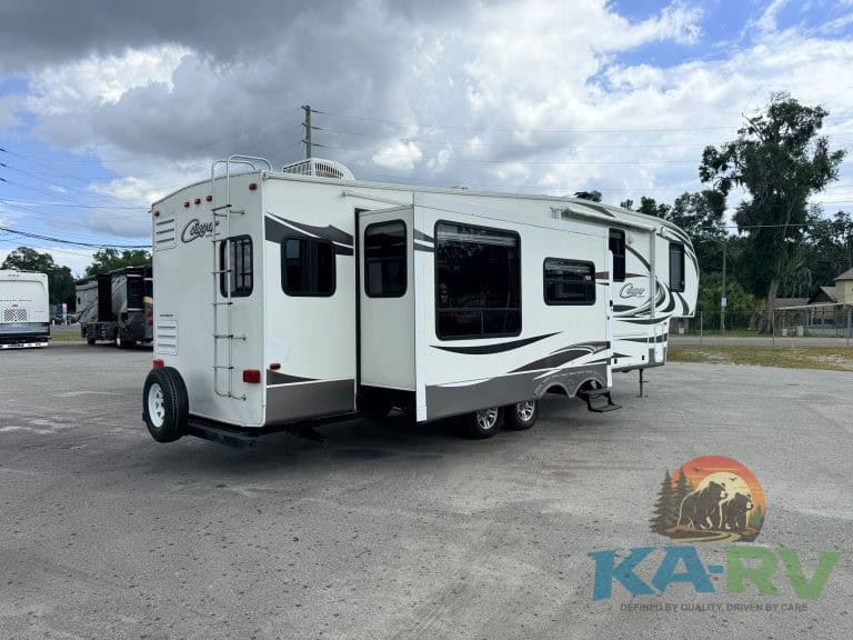 Modern white travel trailer RV with black accents parked outdoors, ready for repair or sale.