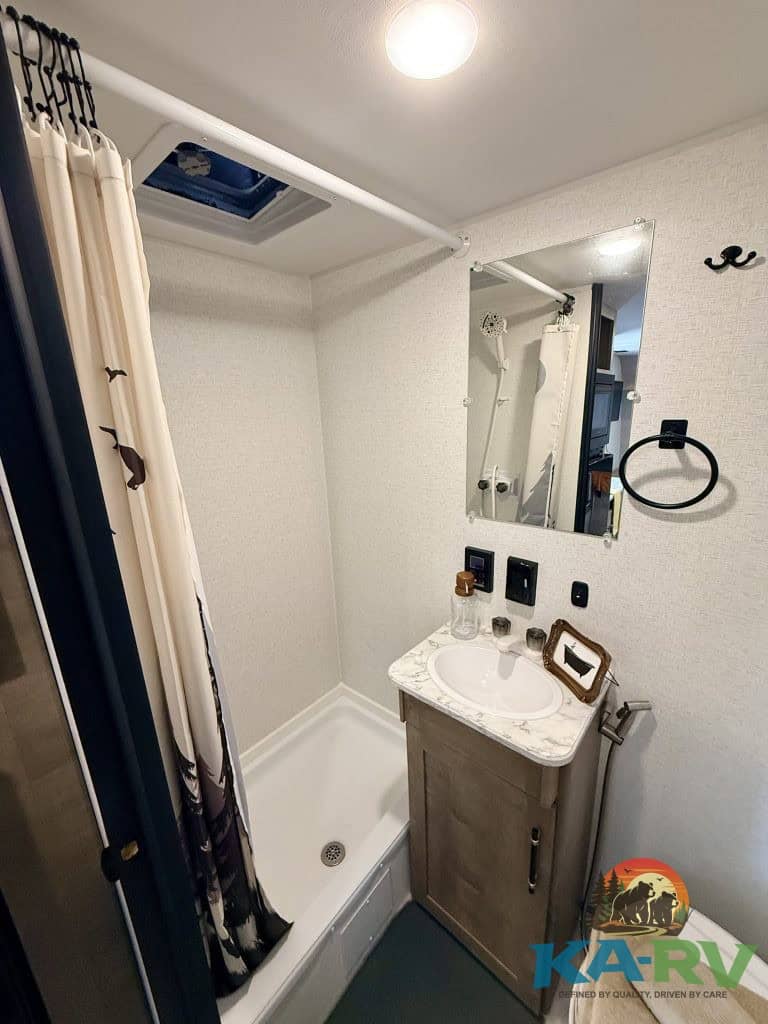 Compact RV bathroom with shower, mirror, and sink for Keystone Springdale 1800BH.