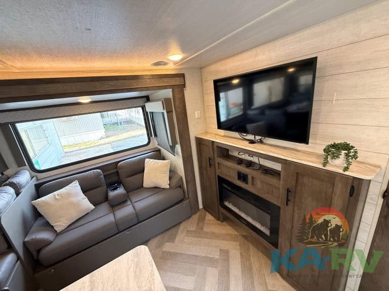 RV interior with sofa, large window, and flat-screen TV for optimal relaxation.