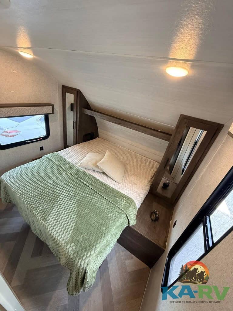 RV bedroom with bed, window, and storage for optimal travel comfort.