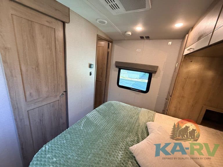RV bedroom interior with cozy bed, wooden cabinetry, and a window for natural light. Perfect for tra.