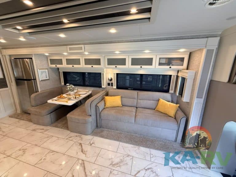 Modern RV interior with sofa, dining area, and storage cabinets.