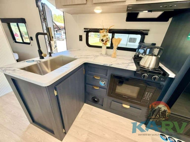 Modern RV kitchen with sink, microwave, and stove in 2026 Acclaim 2700BH.