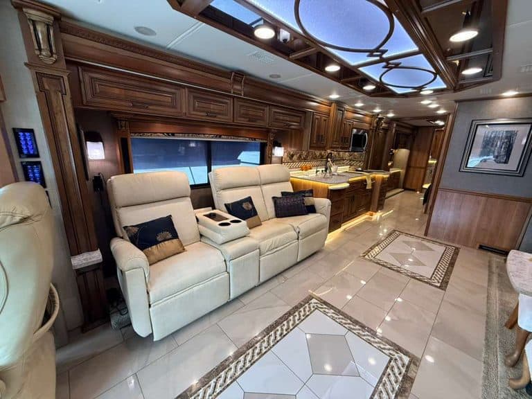 Luxury RV interior with leather sofas, wooden cabinets, and modern lighting.